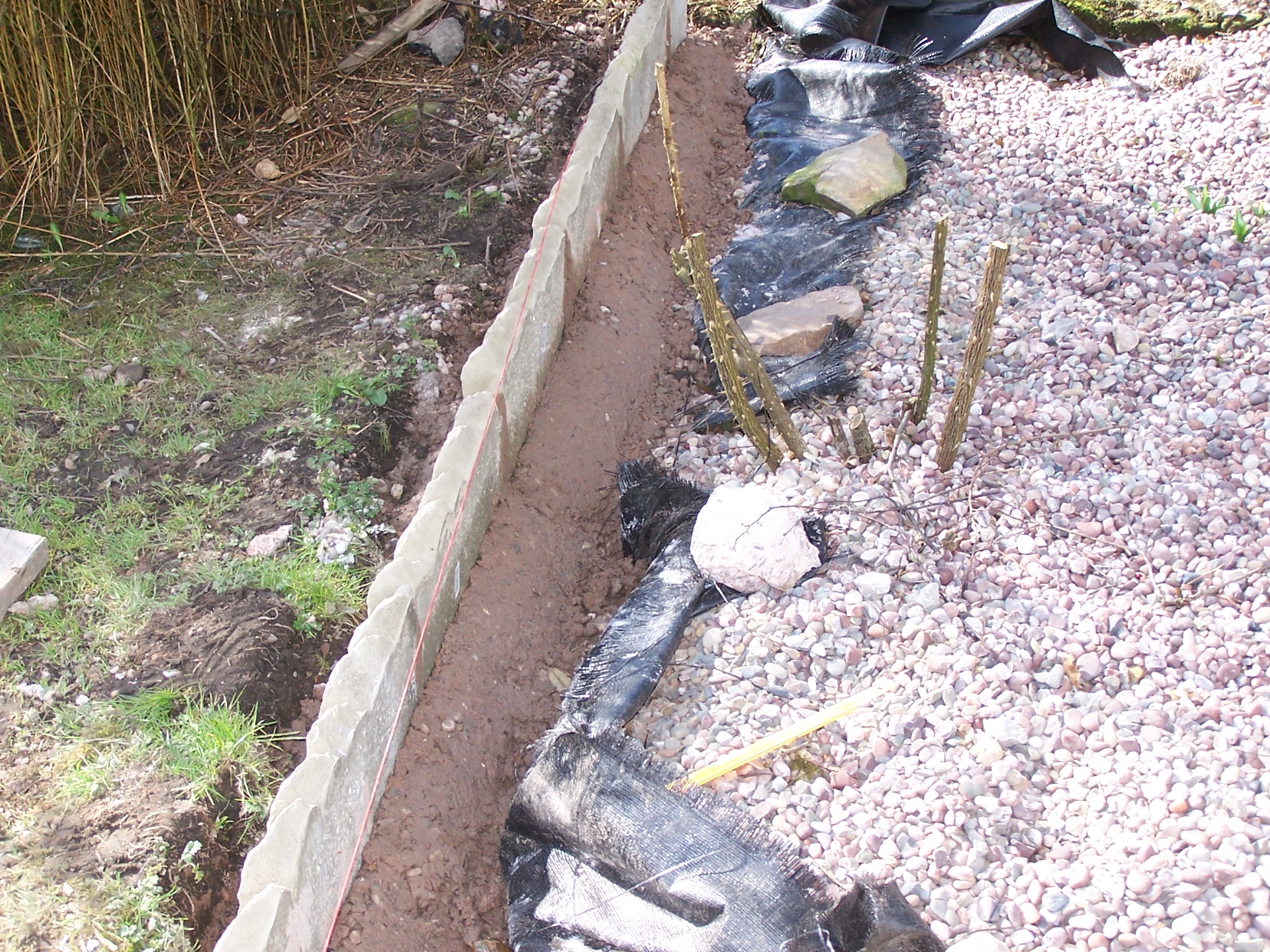 Concrete garden edging set in concrete along edge of the gravel bed