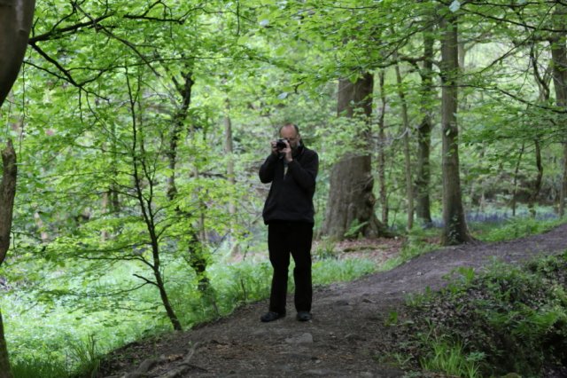 Standing on path through woods taking a photograph