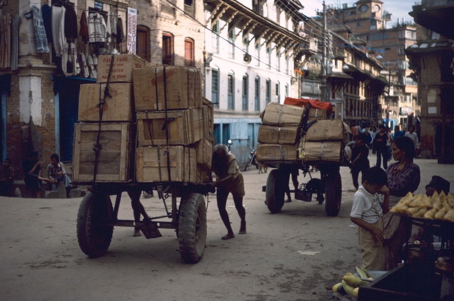 Men pushing carts heavily loaded with crates