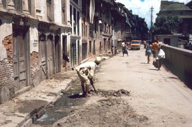 Man repairing pothole in Kathmandu side road