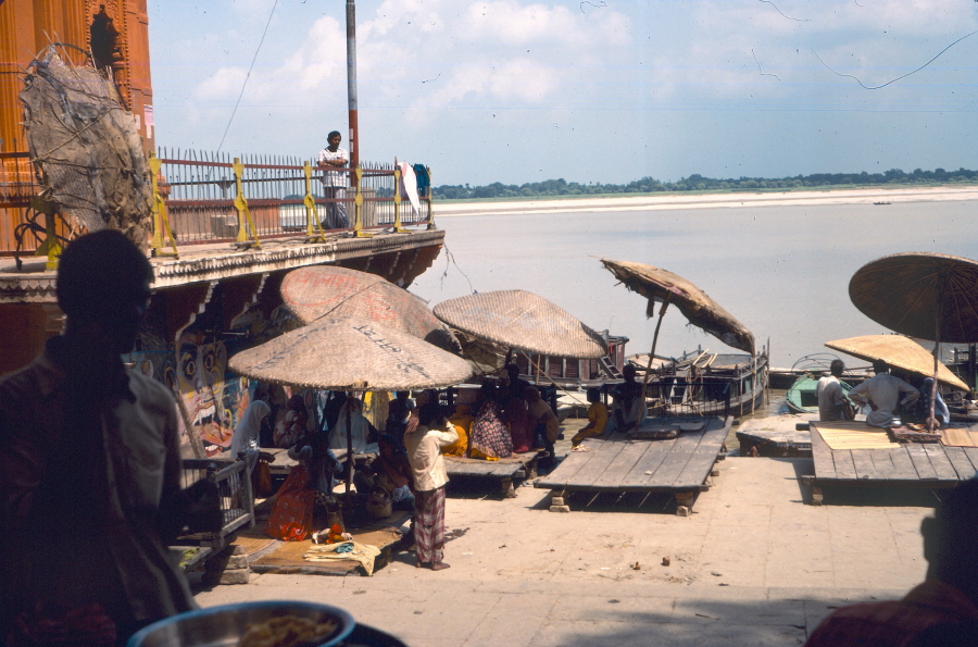 Holy men reading prayers under straw parasols on banks of Ganges