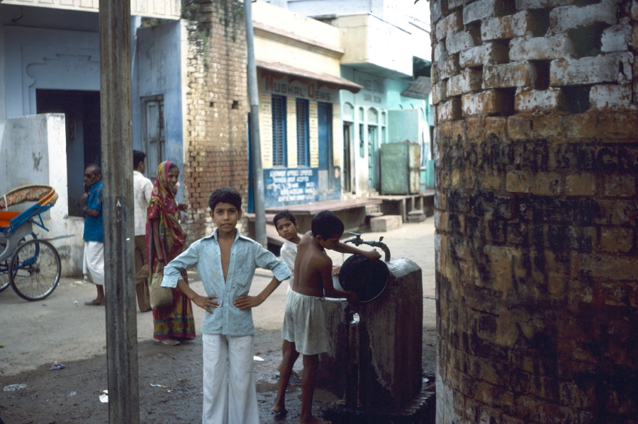 Boy by water pump on street corner