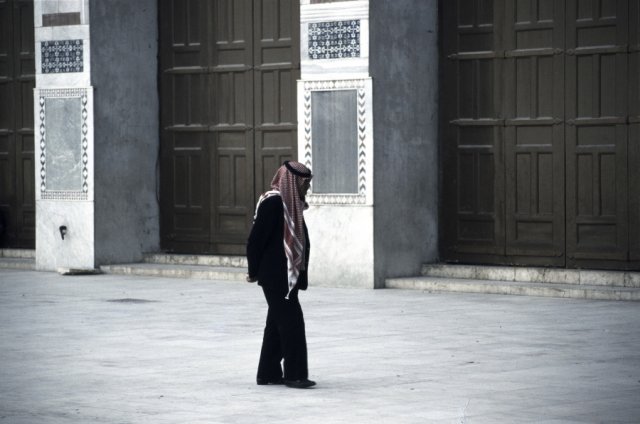 Man in Arab head dress crossing courtyard