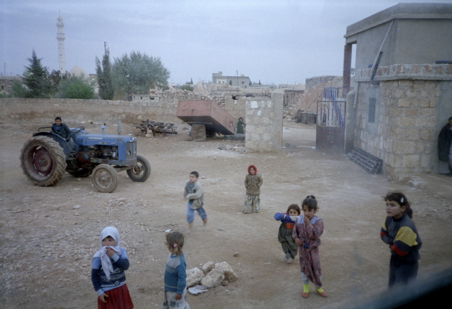 Children playing in courtyard with tractor in background